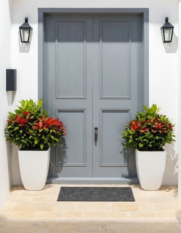 Gray front door with two potted plants on either side on a white wall background