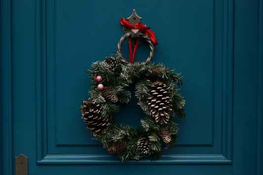 Festively decorated front door with a holiday doormat and wreath