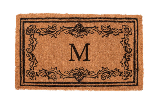 Light brown doormat with decorative border and letter 'M' on a white background