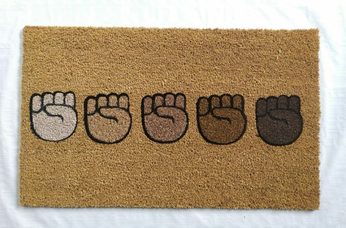 Doormat with five raised fist designs on a beige background