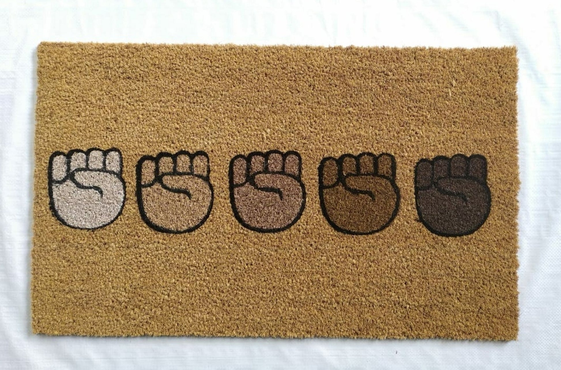 Doormat with five raised fist designs on a beige background