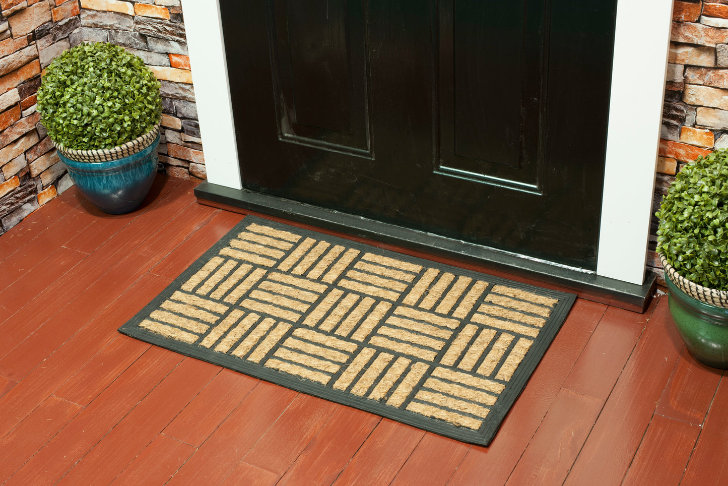 Doormat with geometric pattern on a wooden floor in front of a black door.